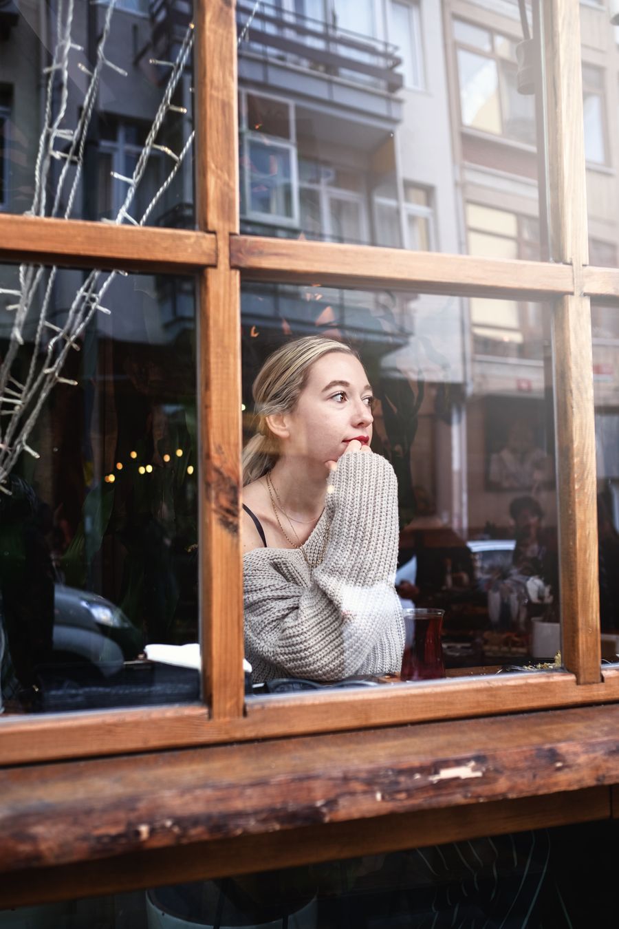 Mujer pensativa mirando por la ventana de un café