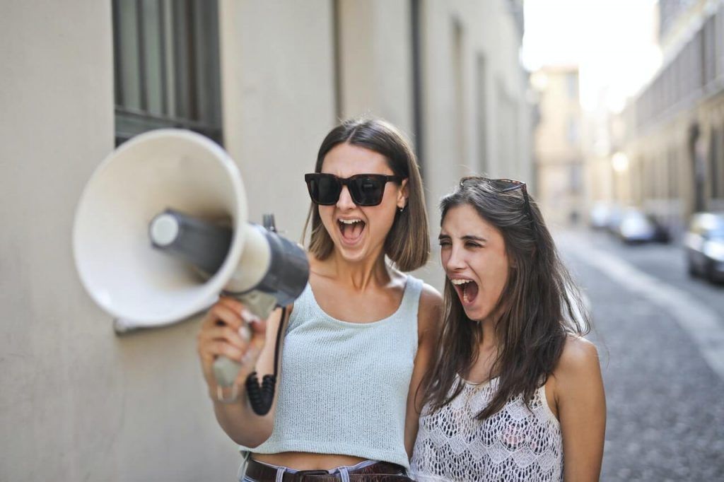 dos mujeres gritando con un altavoz