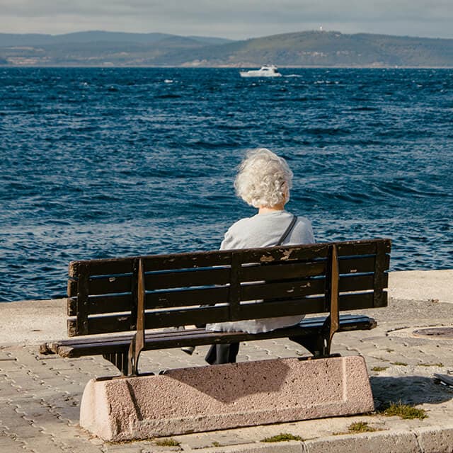 Mujer mayor contemplando el mar, imagen que evoca la reflexión y el asesoramiento filosófico personal